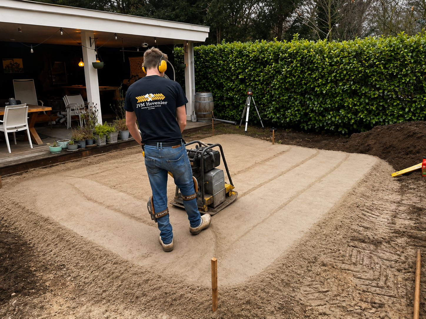Hovenier van JvM Hovenier verdicht het zandbed met een trilplaat voor een nieuw terras in Ermelo